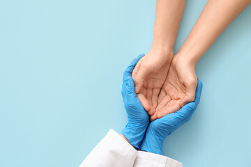 Fototapeta premium Female doctor with patient holding hands on blue background