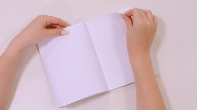 Person is writing in a notebook. The notebook is open to a blank page. The person is using a pen to write