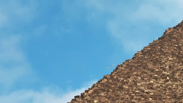 Flock of Birds Flying over the Peak of the Great Pyramid of Khufu at Giza Necropolis against Blue Sky