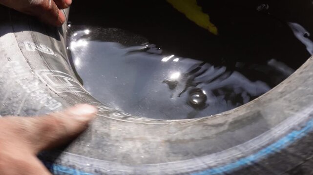 Inspecting a tire for leaks by immersing it in a water tank
