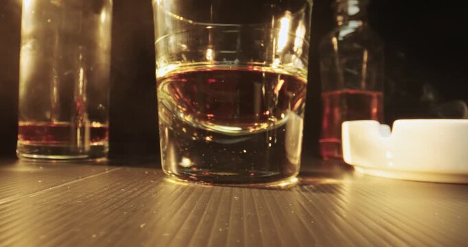 Gambling macro scene. A glass of whiskey, a bottle, smoke of cigar dice on black