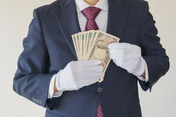 白手袋をはめて現金を数えるスーツ姿の男性