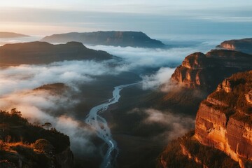 Fototapeta premium Aerial view of a river winding through a mist-covered canyon at sunrise