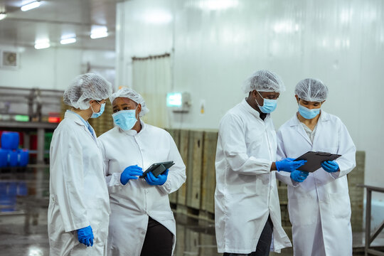 Manufacturing managers perform facility walkthrough and verify sanitation protocol in high volume processing plant. Concept emphasizes food safety governance and audit preparation process.