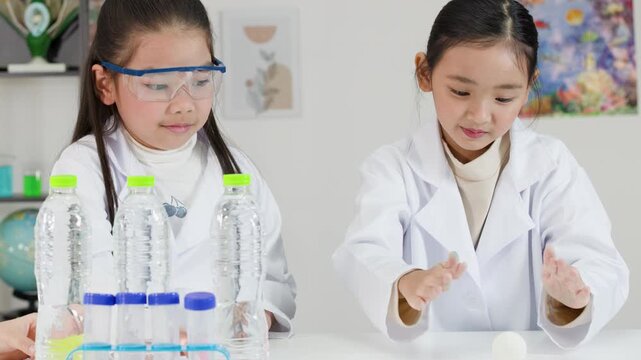 Two Asian Girls in Lab Coats Conduct Bernoulli's Principle Science Experiment