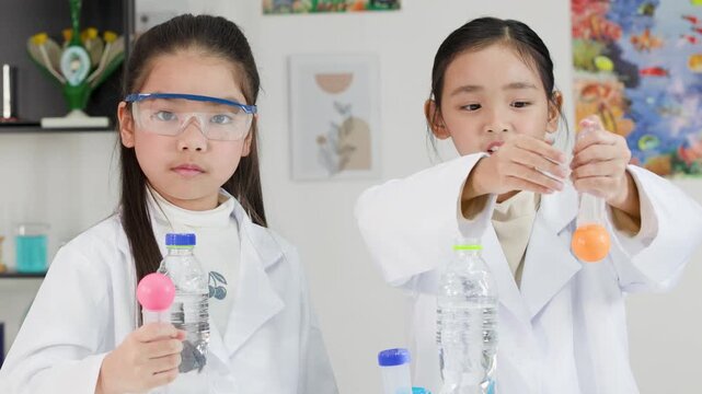 Two Asian Girls Perform Bernoulli's Principle Science Experiment in Classroom