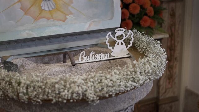 Close view of baptism sign and flowers on church font