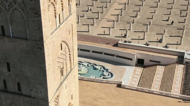 Detailed HD close-up shot of the historical Hassan Tower in Rabat, featuring intricate Almohad carvings with the pillars square and a geometric fountain in the background. Captures the essence of Moro
