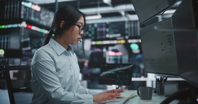 Female Trader Executing Stock and Cryptocurrency Deals in Innovative Digital Office. Focused Asian Broker Trading Global Assets Multi Monitor Workstation With Tablet. Professional Market Execution.