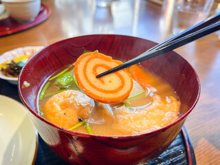 大根、人参、練り物など具沢山味噌汁。金沢で有名な赤巻というナルトのクローズアップ。