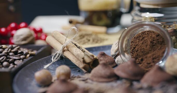 Dried cinnamon rolled in sticks and tied with rope arranged in rustic style with roasted beans of coffee, chocolate and hazzelnut and refined sugar on a wooden table, cinematic isolated shot