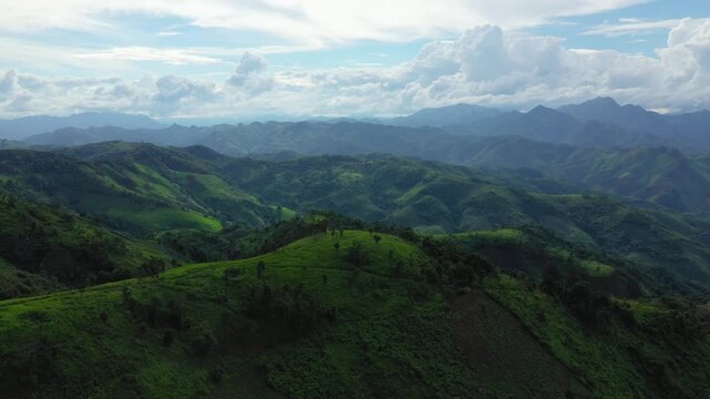 Aerial view of rolling green hills and mountains under a dramatic sky in the countryside between Phonsavan and Phou Khoun, Laos.