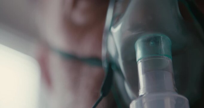 Close up of elderly patient wearing respiratory face mask for oxygen therapy indoors. Ideal for home healthcare, breathing difficulty, and medical support visuals.