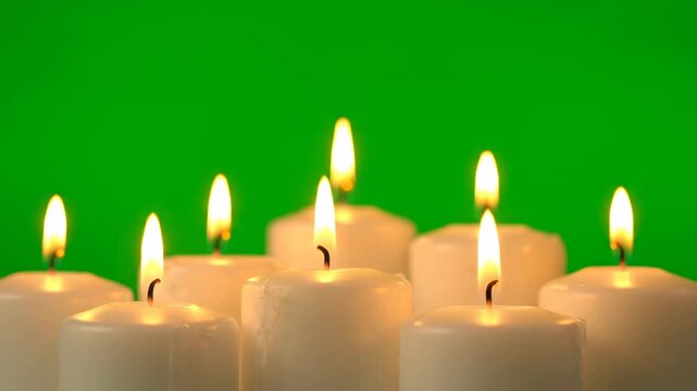 A group of varying height pillar candles, their flames gently swaying in unison on green screen organic movement, background, dynamic