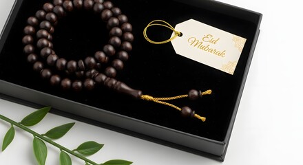 Naklejka premium Prayer beads beautifully presented in a black gift box with a decorative tag and a green leafy stem on a white surface