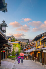Obraz premium Traditional wooden houses, featuring a woman in a kimono surrounded by spring cherry blossoms in Kyoto
