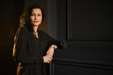 Woman stands by a black wall with a small skull in a dimly lit room during an indoor event © boomeart