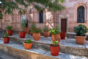 Potted flowers and leafy plants on stone steps in the calm courtyard at Nea Moni monastery on Chios island, Greece