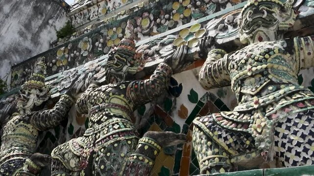 Ornate statues of protectors holding temple cornices and mosaics Wat Arun