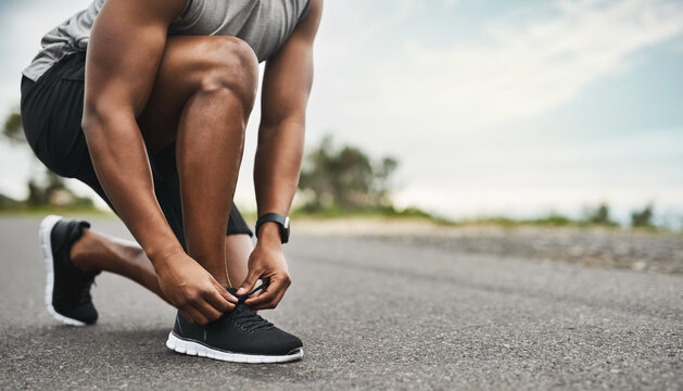 Hands, shoelace and man in street, practice for health benefits and training. Outdoor, athlete and person with sneakers, exercise and fitness for wellness, start day and feet with morning routine