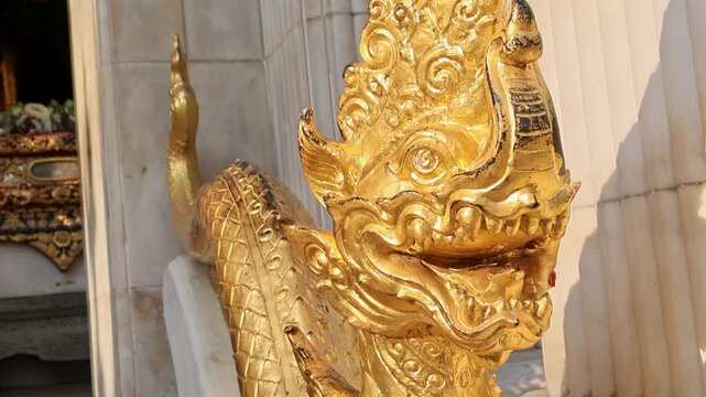 Polished gold guardian statue with jasmine adornment and marble background