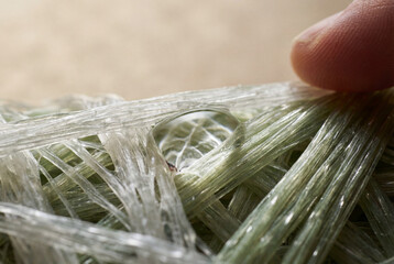 Extreme macro shot of a synthetic fiber structure with a crystalline droplet. The image captures the intricate micro-topography and light refraction, highlighting the pinnacle of material engineering 