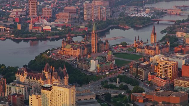 Aerial drone footage sweeping across ottawa downtown core showcasing parliament hill buildings and landmarks alongside the picturesque ottawa river during golden hour