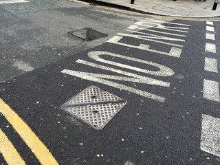Street scene in Manchester UK with No Entry road markings and manhole covers on wet asphalt