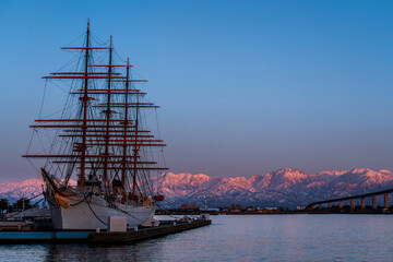 夕方の海王丸パークから新湊大橋と海王丸を前景にピンク色染まる立山連峰アーベンロート