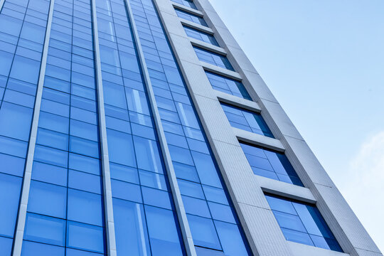 Office building glass facade reflecting sky in urban setting