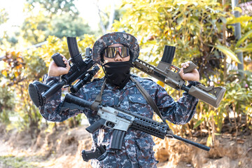 Obraz premium Confident soldier in camouflage uniform holding military rifle and weapon. tactical man in combat gear posing with gun outdoors, showing force and power