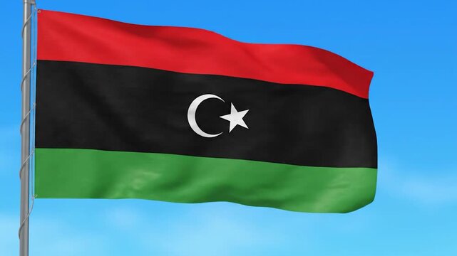 The national flag of Libya proudly waves in the wind against a clear blue sky