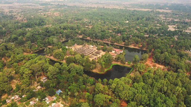 Drone shot of Bakong temple surrounded by dense forest and moats in Cambodia, showcasing ancient architecture and natural landscape.