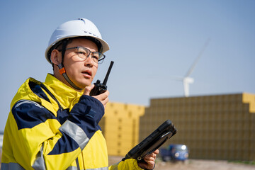 Engineer at wind farm holding walkie-talkie during on-site inspection