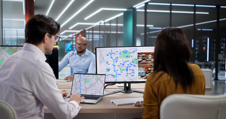 Diverse Team Studies City Maps On Laptops, Planning Land And Property