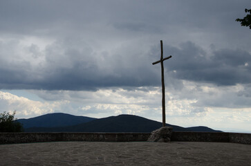 Obraz premium Simple Wooden Cross on Hilltop Against Stormy Sky