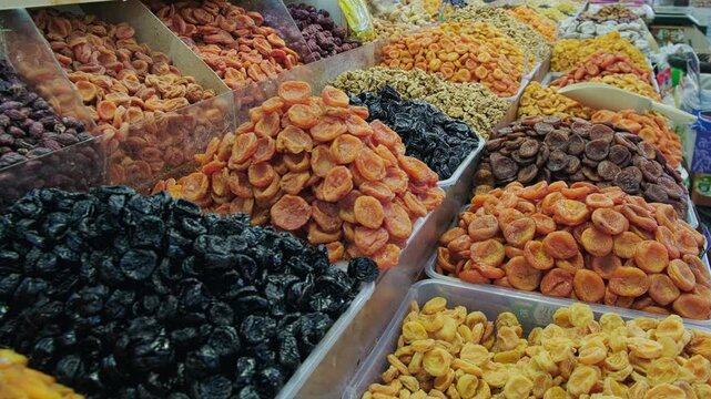 Vibrant market display featuring large trays filled with assorted dried fruits such as apricots, prunes, dates and figs. Traditional local market or grocery bazaar