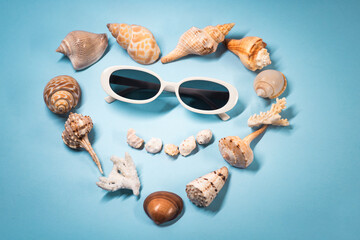 Obraz premium Smiling Beach Concept Sunglasses And Seashells On Blue Background Flat Lay