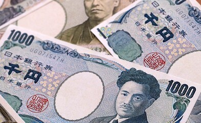 Japanese yen money bills pile on table. Japan banknotes of JPY currency close up. © Larysa