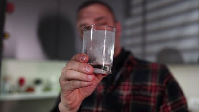 Man drinking effervescent tablet solution at home.