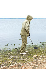 A man with a metal detector on the shore of a reservoir.