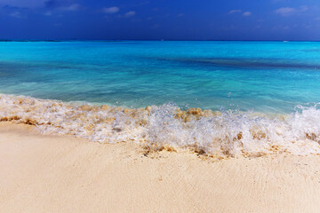 Crystal waves crash onto golden sand
