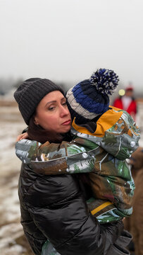 A woman with a child in her arms and emotions on her face in winter, military conflict, refugees.