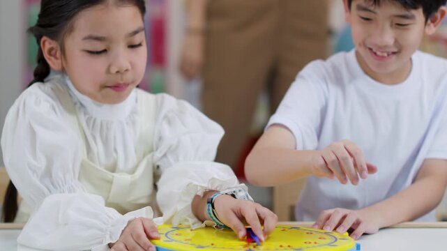 Asian Children Learning to Tell Time with Clock Toy in Classroom