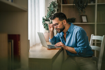 Man working on laptop at home office desk