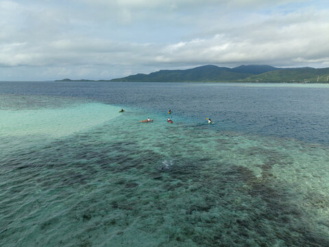 Aerial view of azure waters meet the horizon near Menjangan Kecil Island, a tropical haven under a cloudy sky, Karimunjawa, Central Java, Indonesia.