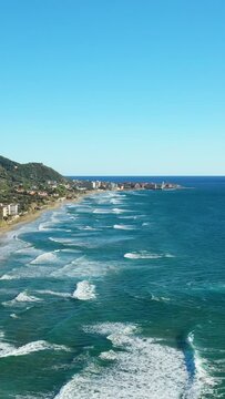 Scenic aerial view of the turquoise sea and coastline with distant buildings and hills in Acciaroli, Italy, under a clear blue sky.
