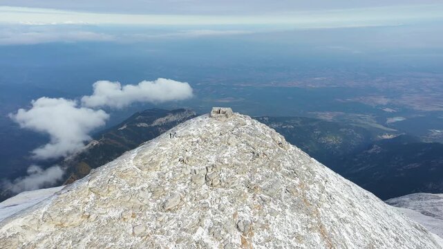 Slow panning drone shot of the Chapel of the Prophet Elias on Profitis Ilias peak of Mount Olympus, surrounded by fresh snow under overcast skies