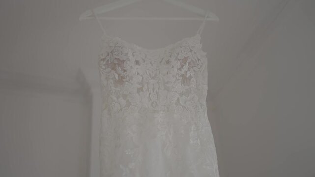 White lace wedding dress on hanger against wall