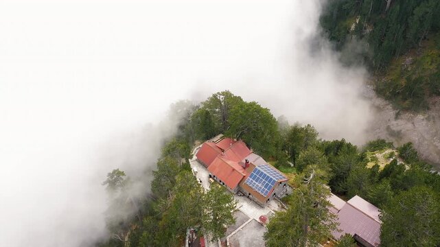Panoramic aerial view of Petrostrouga Refuge surrounded by pine forest and drifting fog. Mount Olympus, Greece